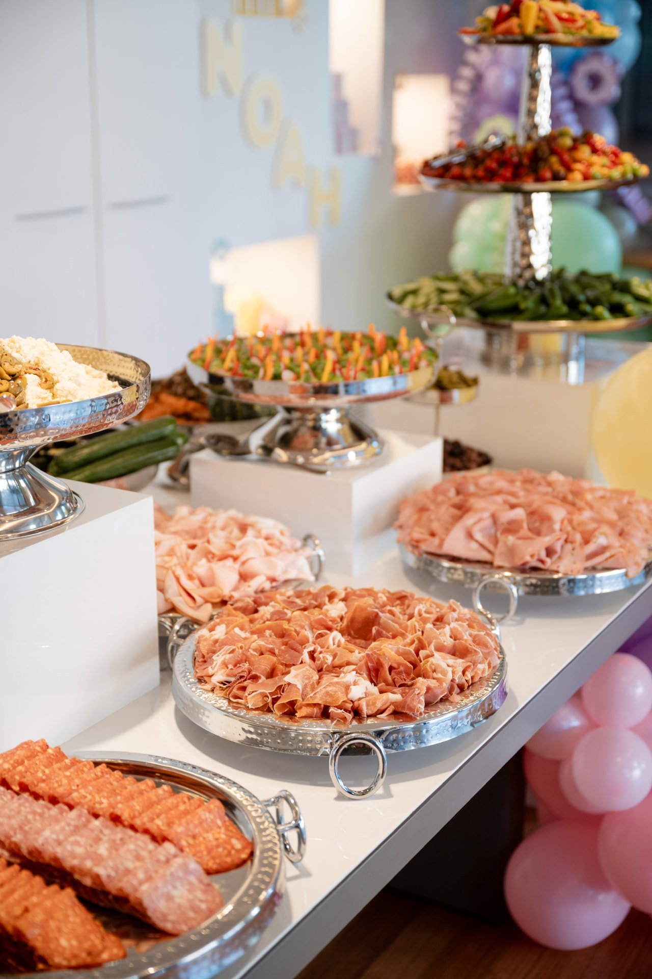 Cured meats and produce laid across a tiered buffet table