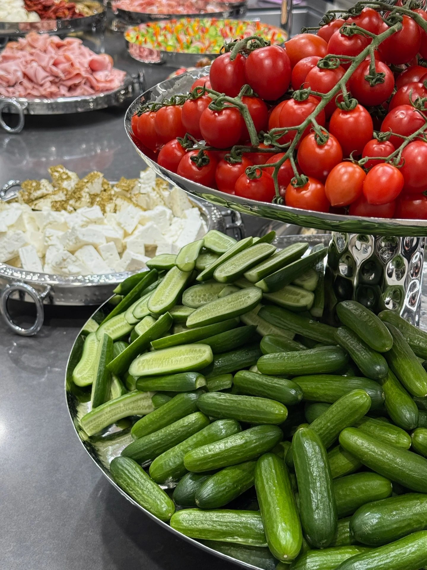Tiered silver stand of cucumbers and vine tomatoes